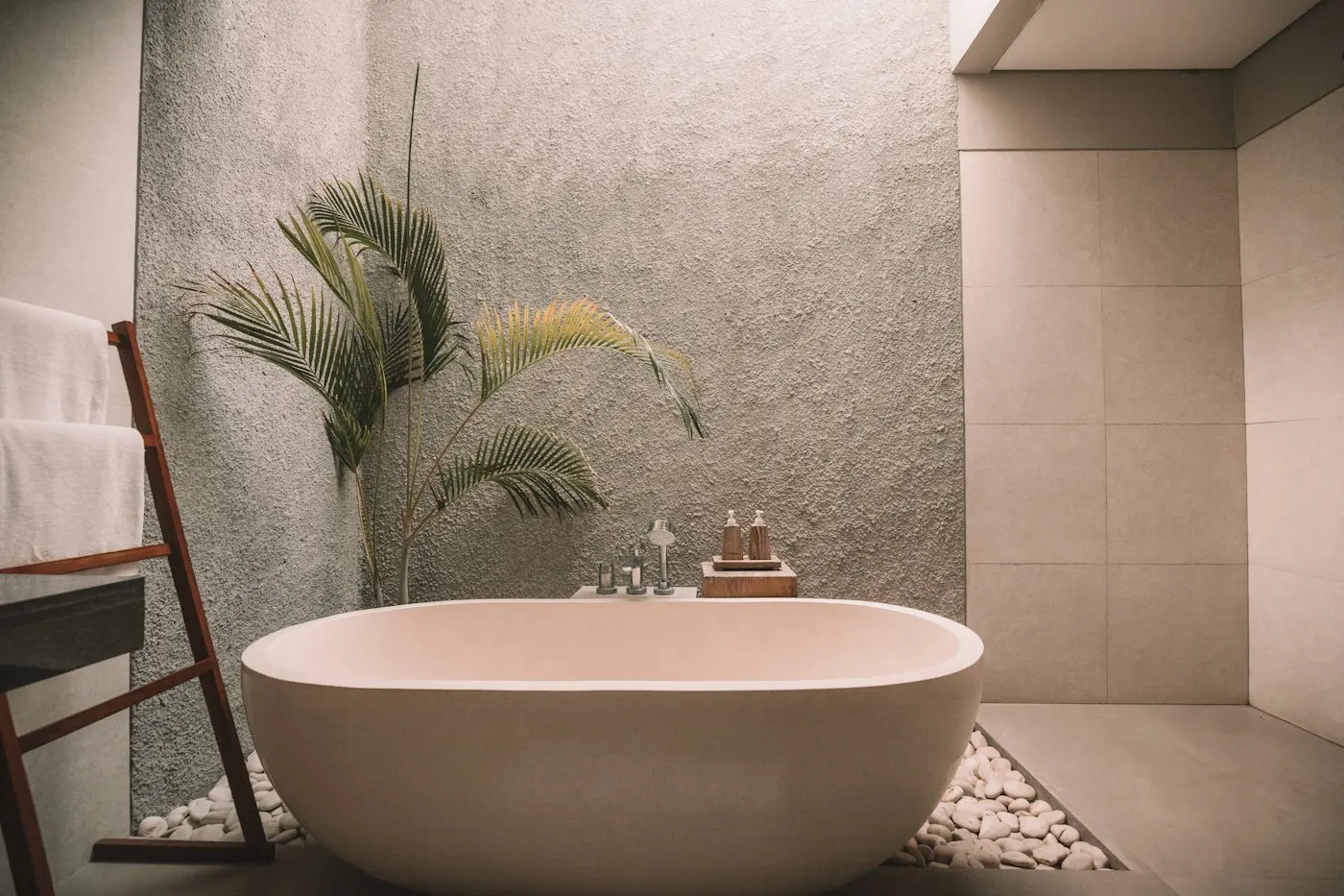 Freestanding stone bath in a room of textured limestone and plaster, softly lit