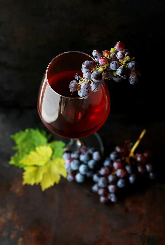 Glass of red natural wine beside dark grapes