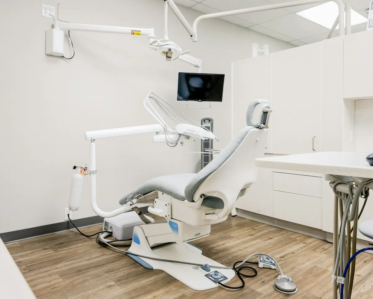 Helles Behandlungszimmer mit Behandlungsstuhl, Monitor und Holzboden